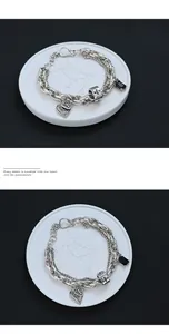 Dettaglio di bracciale argento vintage con ciondoli a croce, cuore e zirconi neri