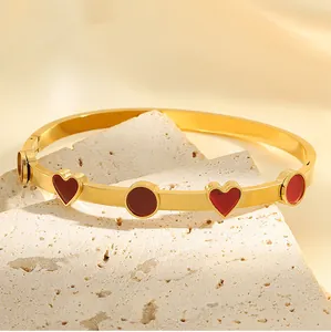 Gros plan détaillé d'un bracelet jonc en acier titane doré avec cœurs et cercles rouges