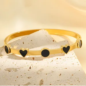 Vue détaillée d'un élégant bracelet jonc en acier doré avec émail en forme de cœur et cercle