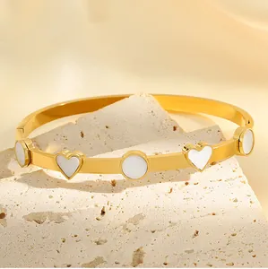 Gros plan d'un bracelet doré en acier titane avec des cœurs en émail blanc