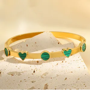 Vue détaillée des breloques cœur et cercle plaquées or 18 carats sur le bracelet vert