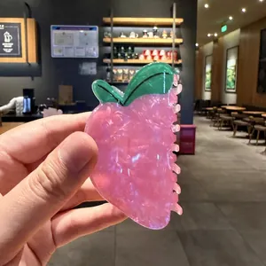 Primer plano de una bonita pinza para el pelo con forma de fresa rosa translúcida