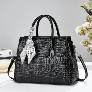 Vue frontale d'un sac à main noir à motif crocodile dans un cadre de studio chic