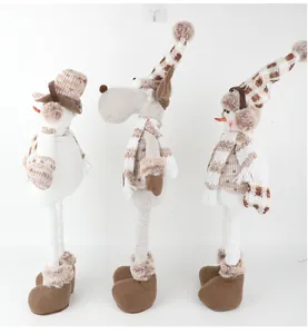 Vue latérale de trois poupées de Noël avec écharpes et chapeaux en maille beige et marron