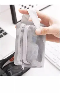 Compact grey nylon mesh storage pouch for coins and keys shown being held by hand