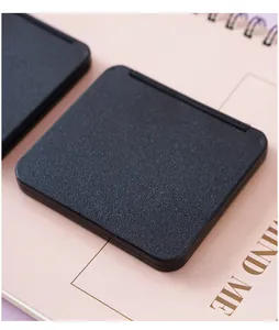 Close-up of a minimalist black portable square folding makeup mirror with textured cover.