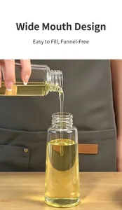 Close-up of clear glass oil bottle being filled showing wide mouth design for easy pouring.