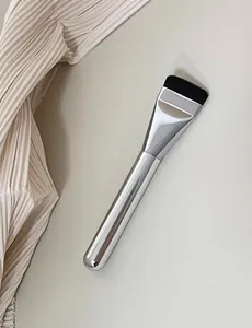 Close-up of an ultra-thin flat head foundation brush with a sleek silver handle