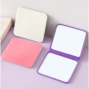 Compact folding double-sided square makeup mirrors in pastel pink, white, and purple.