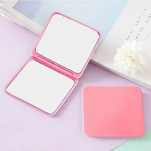 Detailed view showing the open dual mirrors of a pink portable square folding compact mirror