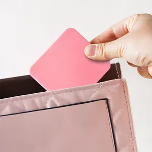 Detail view of a portable pink mini square makeup mirror being put into a pouch