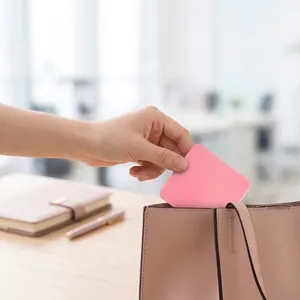 Compact pink square makeup mirror being placed in a stylish brown handbag