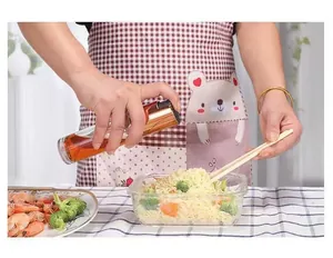 Glass oil sprayer bottle for cooking, spraying oil on noodles in a kitchen setting