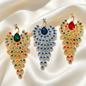Détail de trois broches paon colorées en or et argent avec des strass brillants