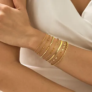 Gros plan de bracelets multicouches dorés empilés avec motifs de corde torsadée et maillons