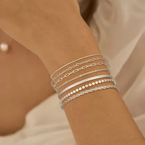 Vue détaillée de bracelets argentés multicouches au poignet avec chaînes torsadées