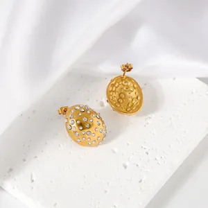 Macro detail of gold-plated stainless steel teardrop earrings with rhinestones.