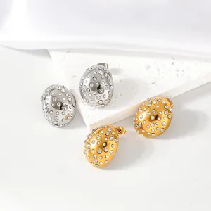 Macro view of gold and silver waterdrop stud earrings with mini pearls and sparkling crystals.