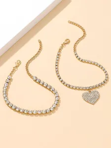 Close-up detail of two gold-toned rhinestone anklets with a sparkling heart charm