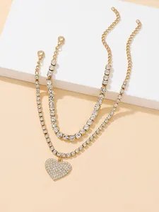 Detailed macro view of a two-piece gold rhinestone anklet set with a heart pendant.