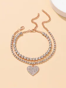 Detailed view of the layered rose gold anklet featuring a rhinestone heart pendant