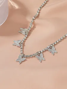 Detailed view of sparkling rhinestone butterfly anklet on elegant champagne silk fabric