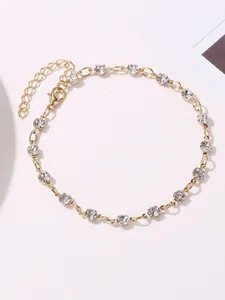 Close-up of elegant gold-tone anklet featuring sparkling clear round rhinestones