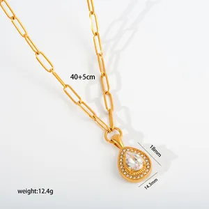 Detailed macro view of golden stainless steel teardrop pendant necklace with clear stones