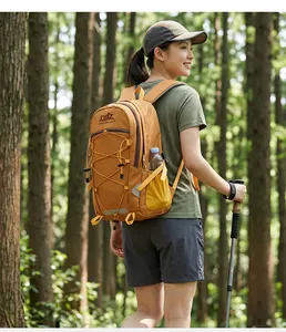 Rückansicht einer Wanderin mit orangefarbenem Rucksack und Trekkingstock im Wald