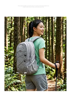 Lächelnde Frau mit großem grauem Wanderrucksack bei einer Trekkingtour im Wald