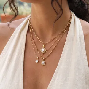 Close-up of triple-layered gold stainless steel necklaces with geometric crystal pendants