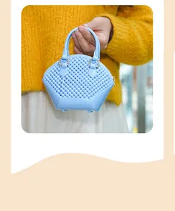 Macro view of a mini light blue beaded shell jelly bag with top handle held by hand
