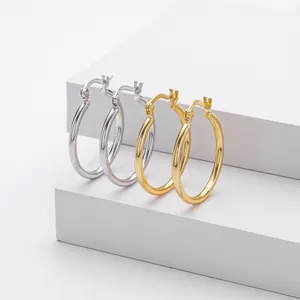 Macro detail of S925 sterling silver hoop earrings in silver and gold on white pedestals