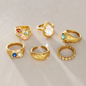 Collezione di anelli dorati martellati con zirconi colorati e una pietra a goccia