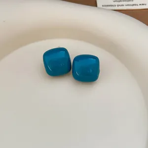 Minimalist teal blue enamel stud earrings with silver needles featuring a rounded square design