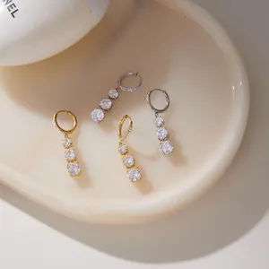 Dettaglio di orecchini classici placcati in oro e argento con triplo zircone