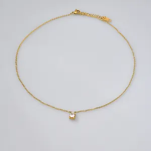 Detail view of a gold stainless steel necklace with a single round zircon pendant.