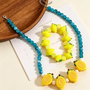 Detailed view of handmade blue bead necklace and bracelet with resin lemon pendants.