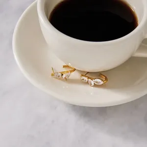 Primer plano de elegantes pendientes de acero dorado con detalles de circonitas