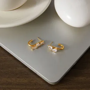 Elegantes pendientes de acero inoxidable dorado con circonitas blancas sobre un portátil