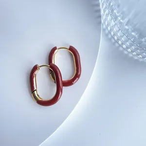 Detailansicht minimalistischer U-förmiger Creolen mit roter Emaille und Goldbeschichtung.