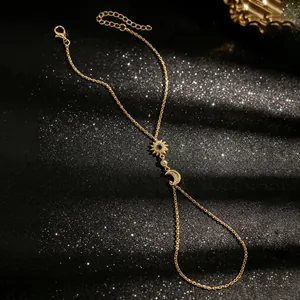 Détail du bracelet de doigt doré avec breloques soleil et lune en zircon