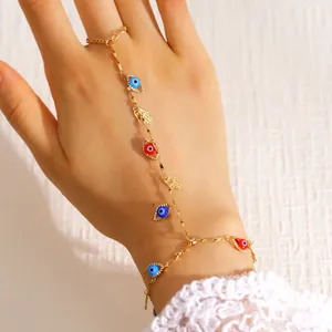 Vue détaillée de la chaîne de main dorée avec des breloques œil et hamsa bleues et rouges
