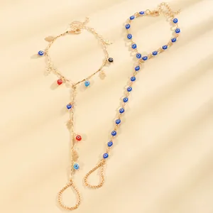 Vue détaillée de bracelets de doigt Evil Eye et Hamsa en or sur un tissu beige élégant