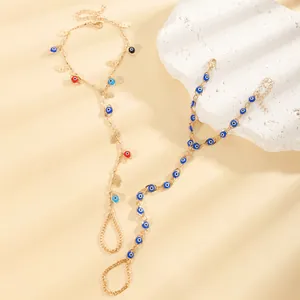 Vue détaillée de bracelets chaîne de doigt dorés avec l'œil porte-bonheur et Hamsa.