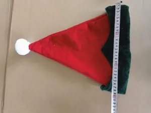 Red and green plush elf Christmas hat with measuring tape showing width detail