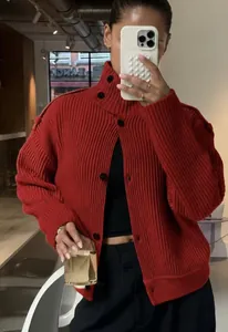 Gros plan d'un gilet en grosse maille rouge vif avec col montant et boutons noirs.