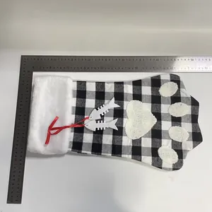 Chaussette de Noël patte de chien à carreaux noir et blanc avec breloques d'arêtes.