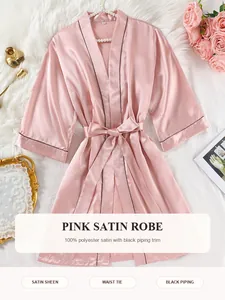 Detailansicht einer luxuriösen rosa Satinrobe mit schwarzer Paspelierung und elegantem Gürtel