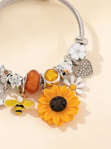 Dettaglio ravvicinato di ciondoli girasole e ape su un braccialetto di perline fai-da-te